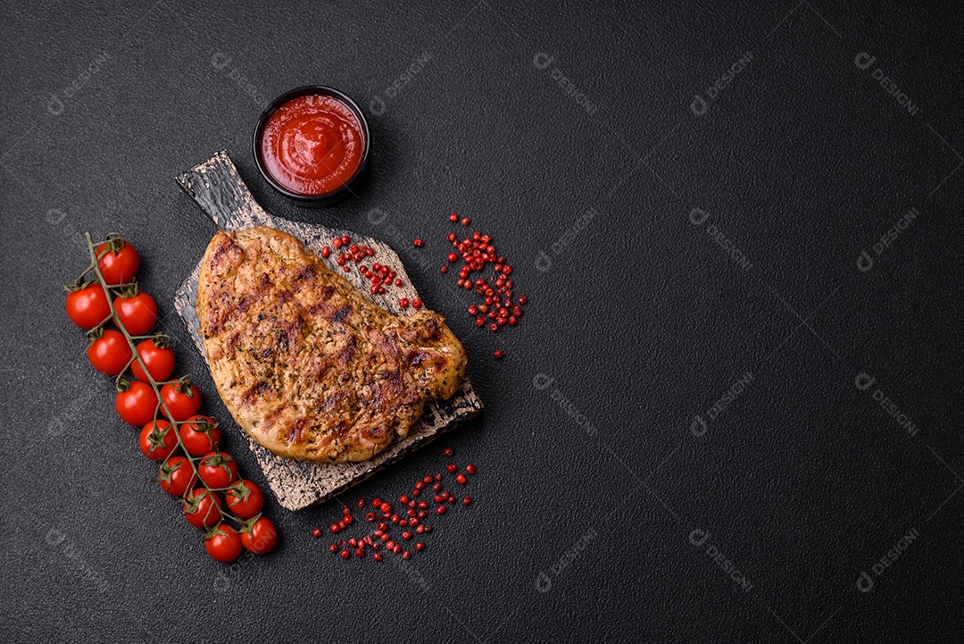 Delicioso bife de porco suculento com sal, especiarias e ervas sobre um fundo escuro de concreto
