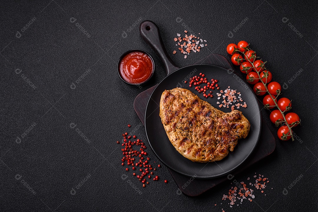 Delicioso bife de porco suculento com sal, especiarias e ervas sobre um fundo escuro de concreto