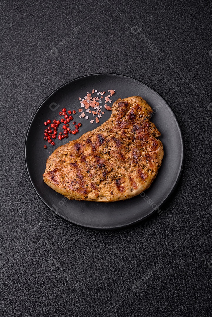 Delicioso bife de porco suculento com sal, especiarias e ervas sobre um fundo escuro de concreto