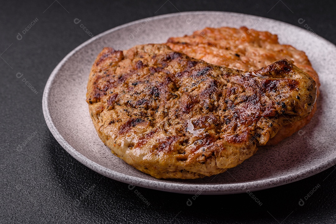 Delicioso bife de porco suculento com sal, especiarias e ervas sobre um fundo escuro de concreto