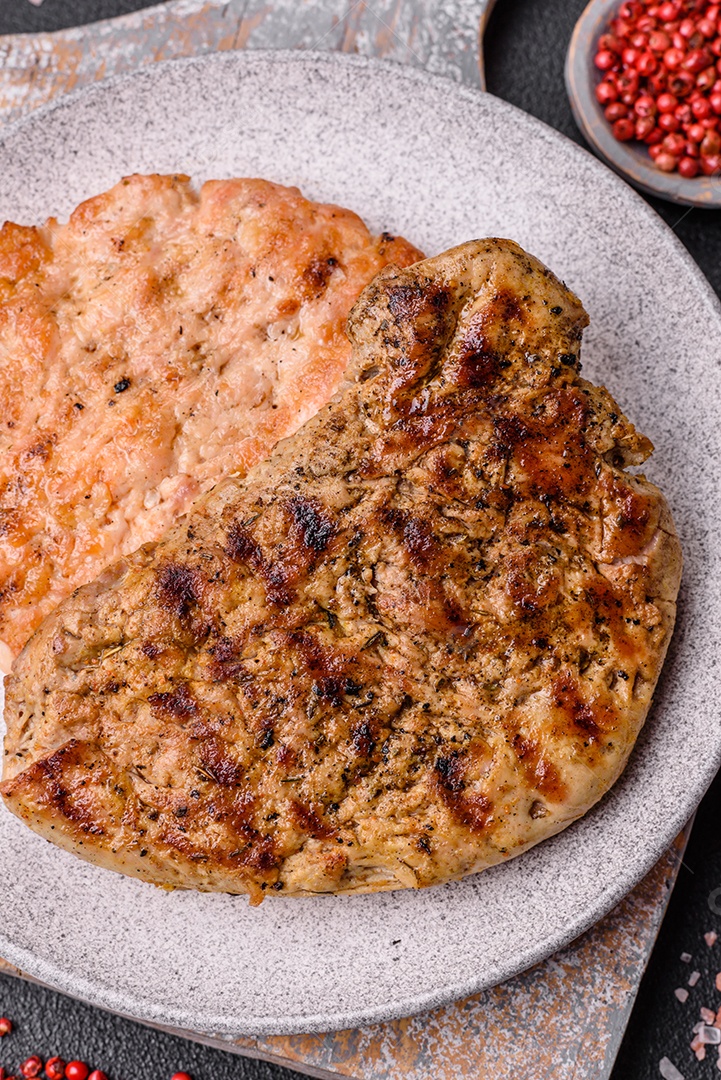 Delicioso bife de porco suculento com sal, especiarias e ervas sobre um fundo escuro de concreto