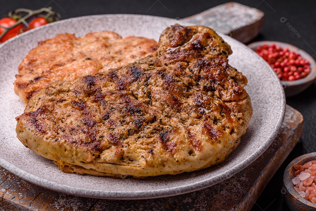 Delicioso bife de porco suculento com sal, especiarias e ervas sobre um fundo escuro de concreto