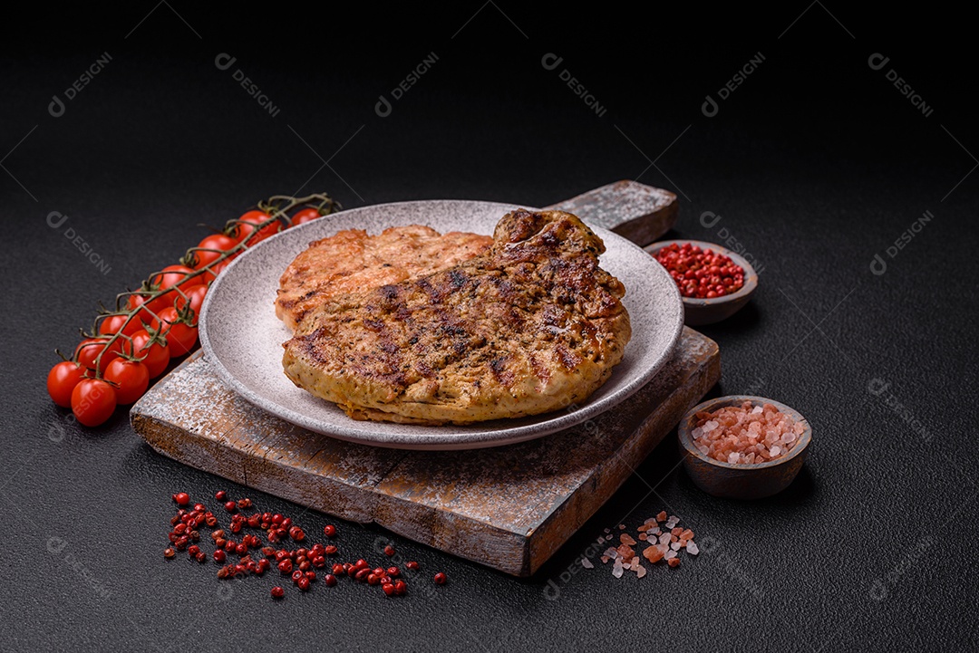 Delicioso bife de porco suculento com sal, especiarias e ervas sobre um fundo escuro de concreto