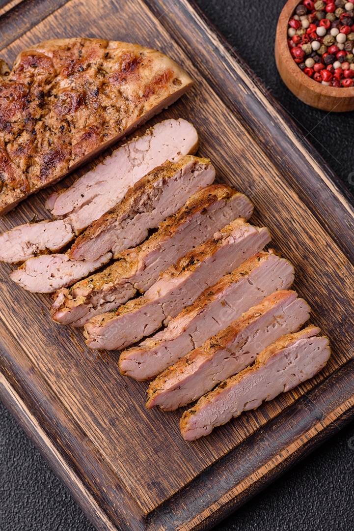 Delicioso peru suculento ou bife de frango com sal, especiarias e ervas sobre um fundo escuro de concreto