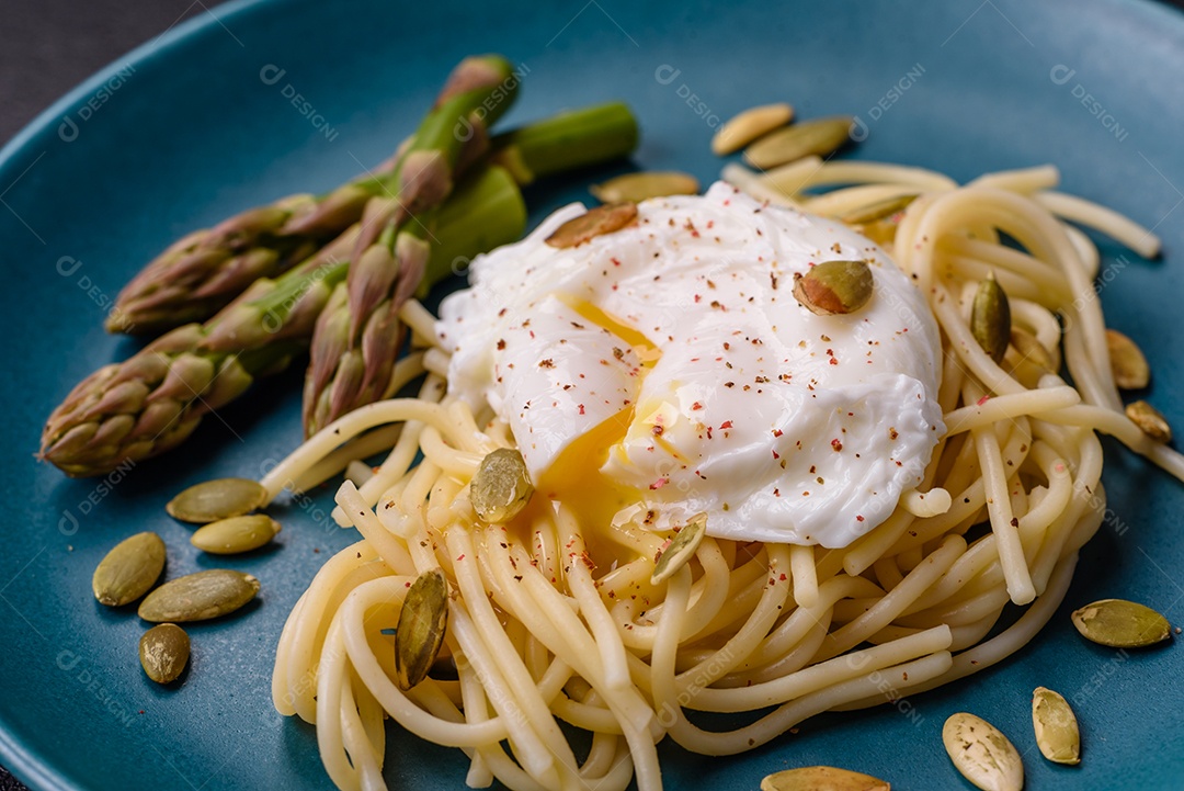 Delicioso café da manhã composto por ovos escalfados com torradas com cream cheese, aspargos, sal e especiarias em um fundo escuro de concreto