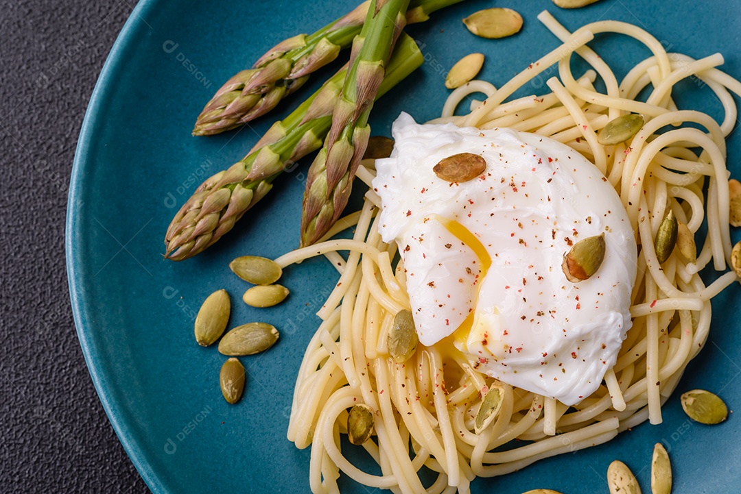 Delicioso café da manhã composto por ovos escalfados com torradas com cream cheese, aspargos, sal e especiarias em um fundo escuro de concreto