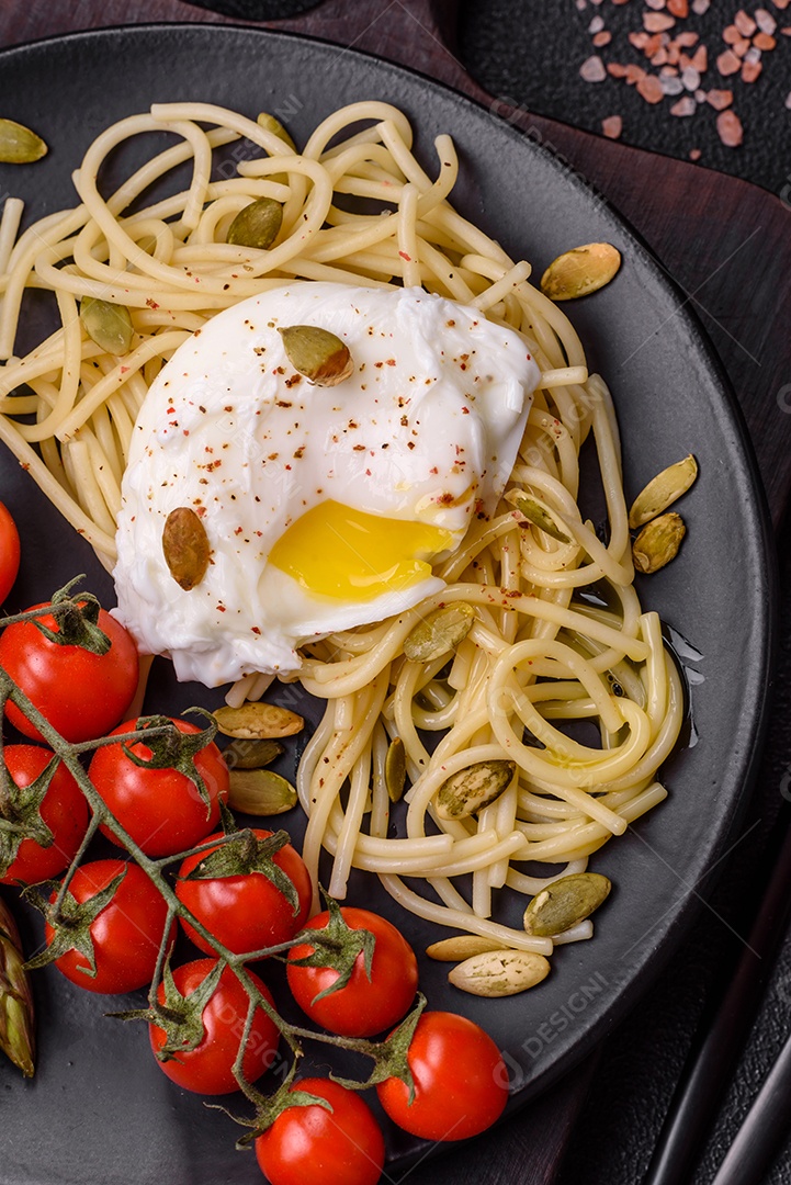 Delicioso café da manhã composto por ovos escalfados com torradas com cream cheese, aspargos, sal e especiarias em um fundo escuro de concreto