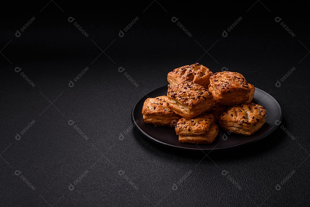 Folhados triangulares com queijo feta, tomate com sal, especiarias e ervas sobre fundo escuro de concreto