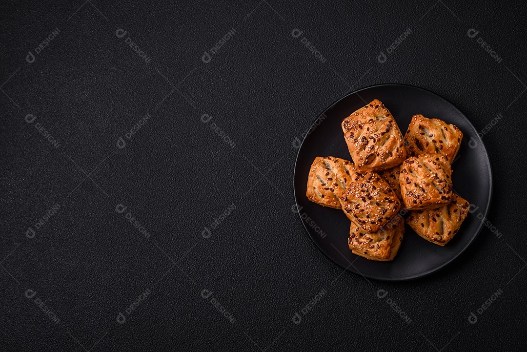 Folhados triangulares com queijo feta, tomate com sal, especiarias e ervas sobre fundo escuro de concreto