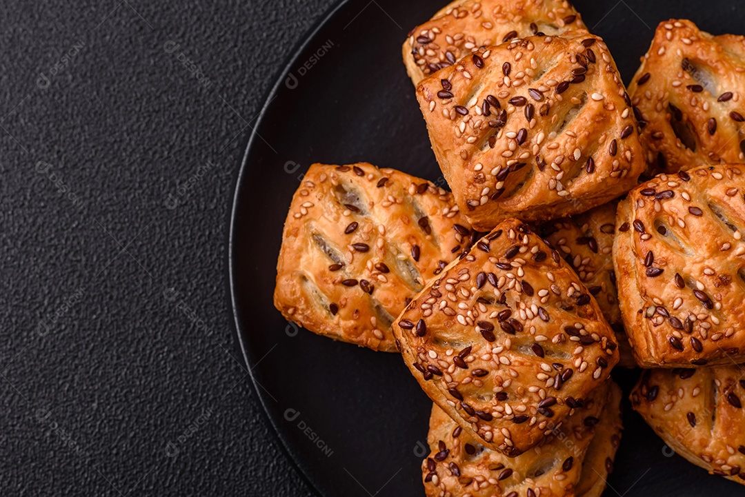 Folhados triangulares com queijo feta, tomate com sal, especiarias e ervas sobre fundo escuro de concreto