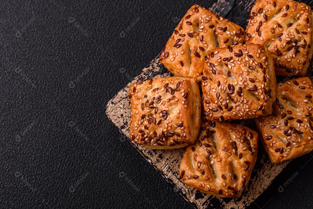 Folhados triangulares com queijo feta, tomate com sal, especiarias e ervas sobre fundo escuro de concreto