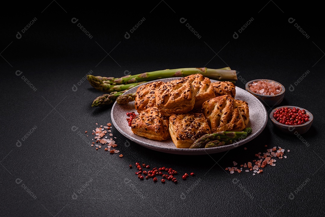 Folhados triangulares com queijo feta, tomate com sal, especiarias e ervas sobre fundo escuro de concreto