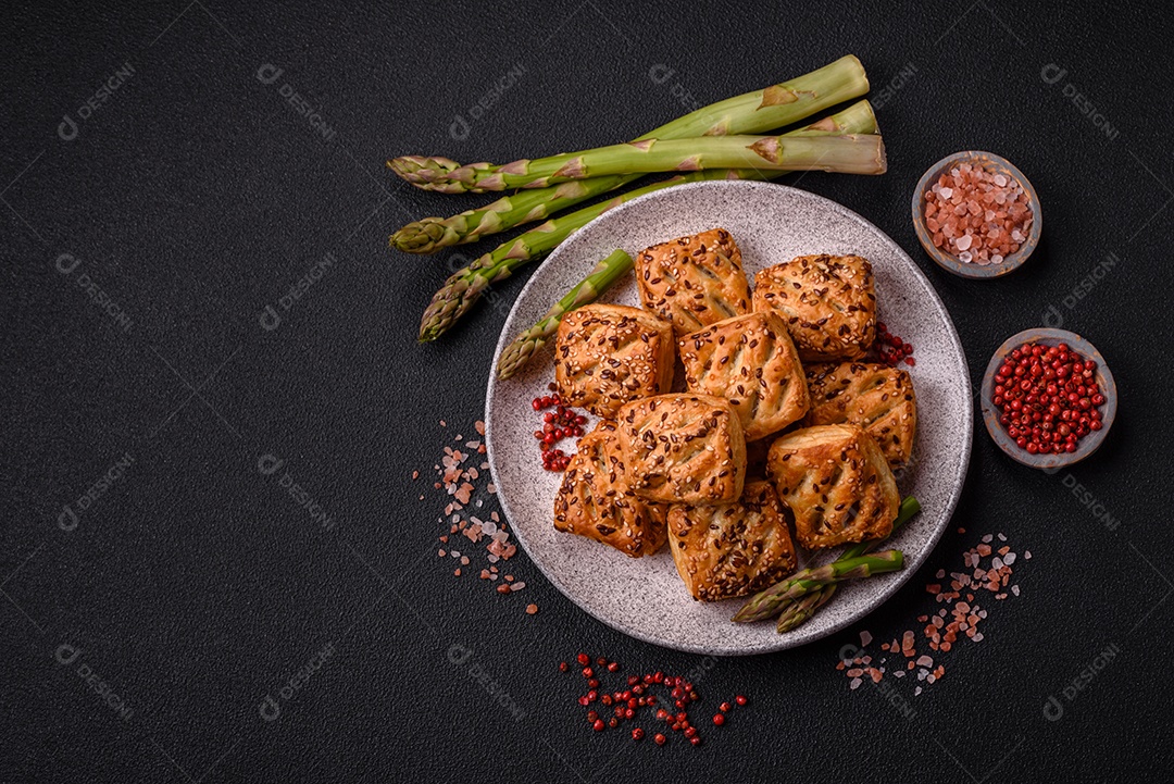 Folhados triangulares com queijo feta, tomate com sal, especiarias e ervas sobre fundo escuro de concreto
