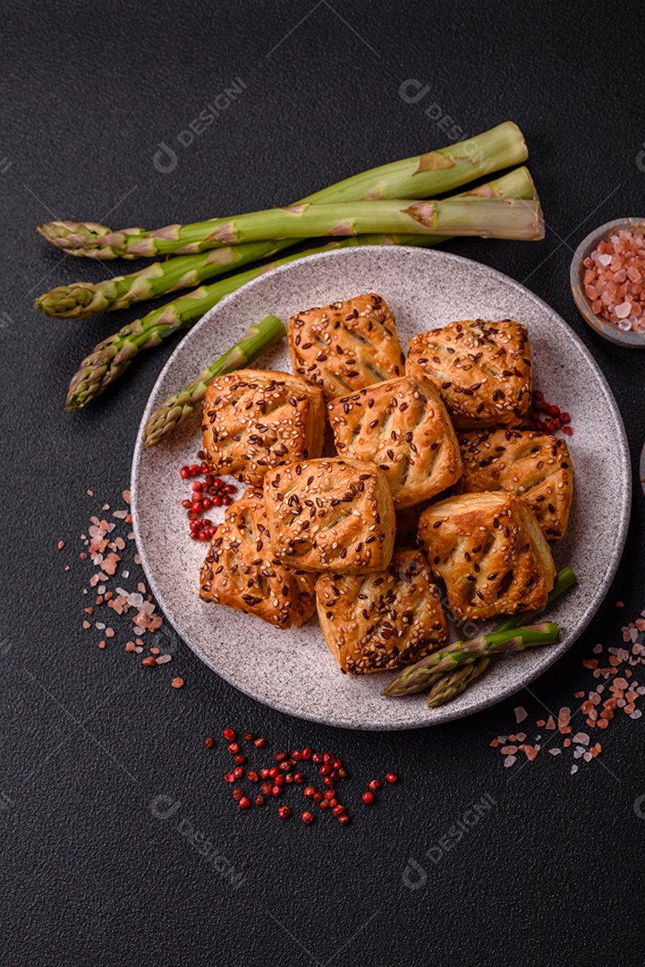 Folhados triangulares com queijo feta, tomate com sal, especiarias e ervas sobre fundo escuro de concreto