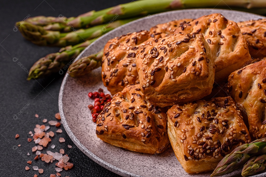 Folhados triangulares com queijo feta, tomate com sal, especiarias e ervas sobre fundo escuro de concreto