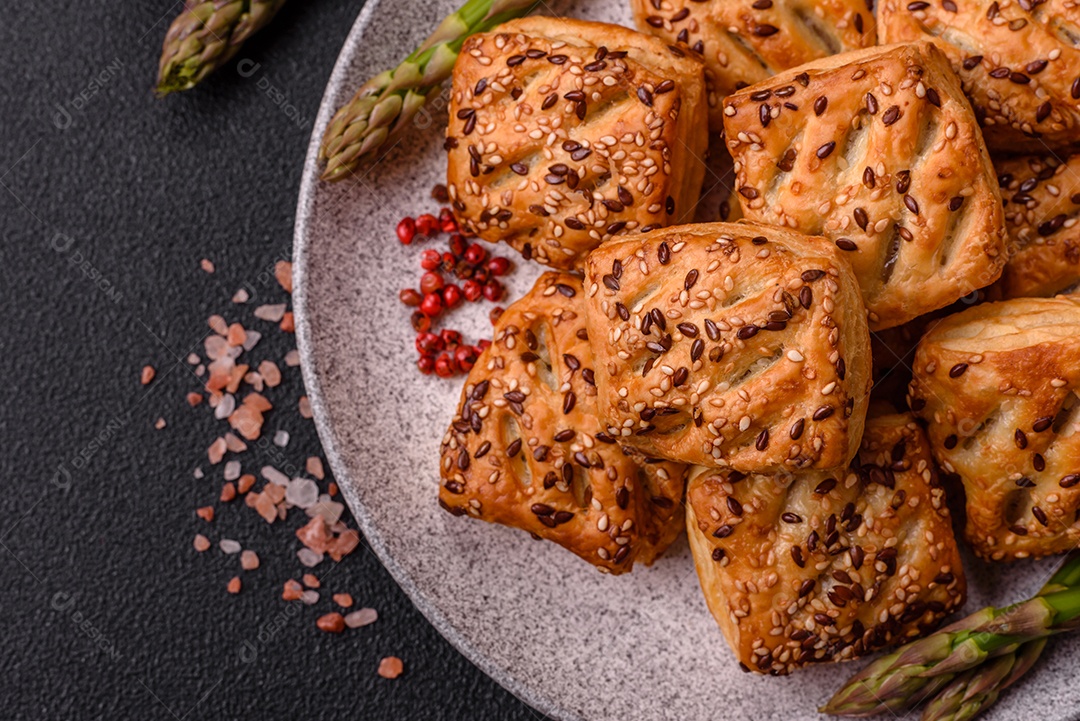 Folhados triangulares com queijo feta, tomate com sal, especiarias e ervas sobre fundo escuro de concreto