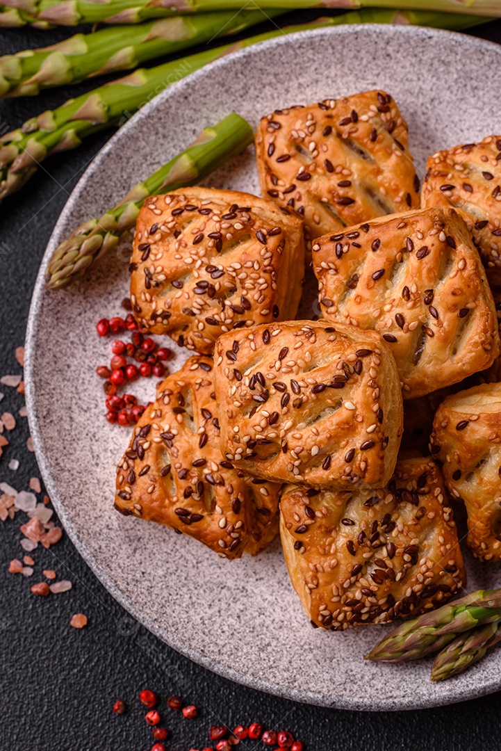Folhados triangulares com queijo feta, tomate com sal, especiarias e ervas sobre fundo escuro de concret