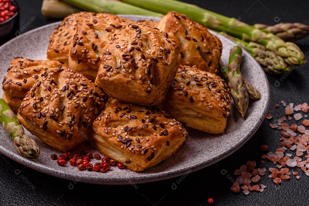 Folhados triangulares com queijo feta, tomate com sal, especiarias e ervas sobre fundo escuro de concreto