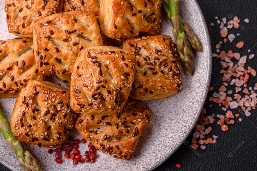 Folhados triangulares com queijo feta, tomate com sal, especiarias e ervas sobre fundo escuro de concreto