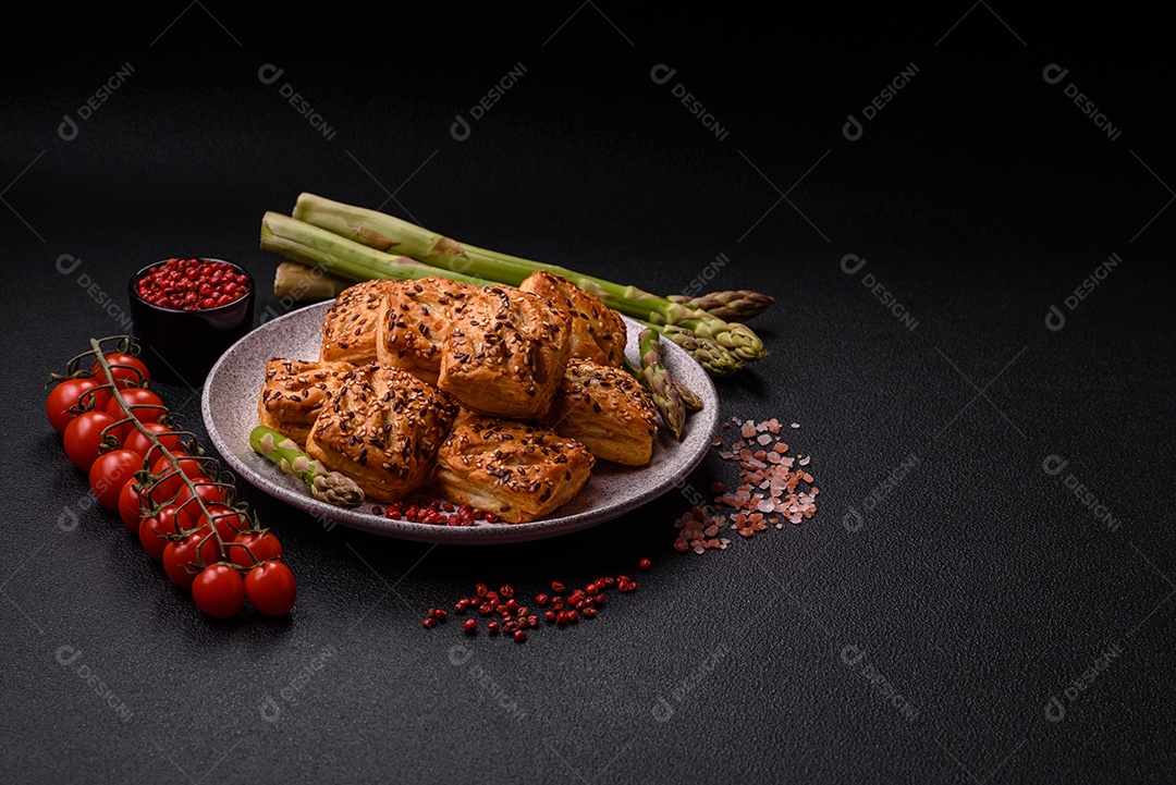 Folhados triangulares com queijo feta, tomate com sal, especiarias e ervas sobre fundo escuro de concreto