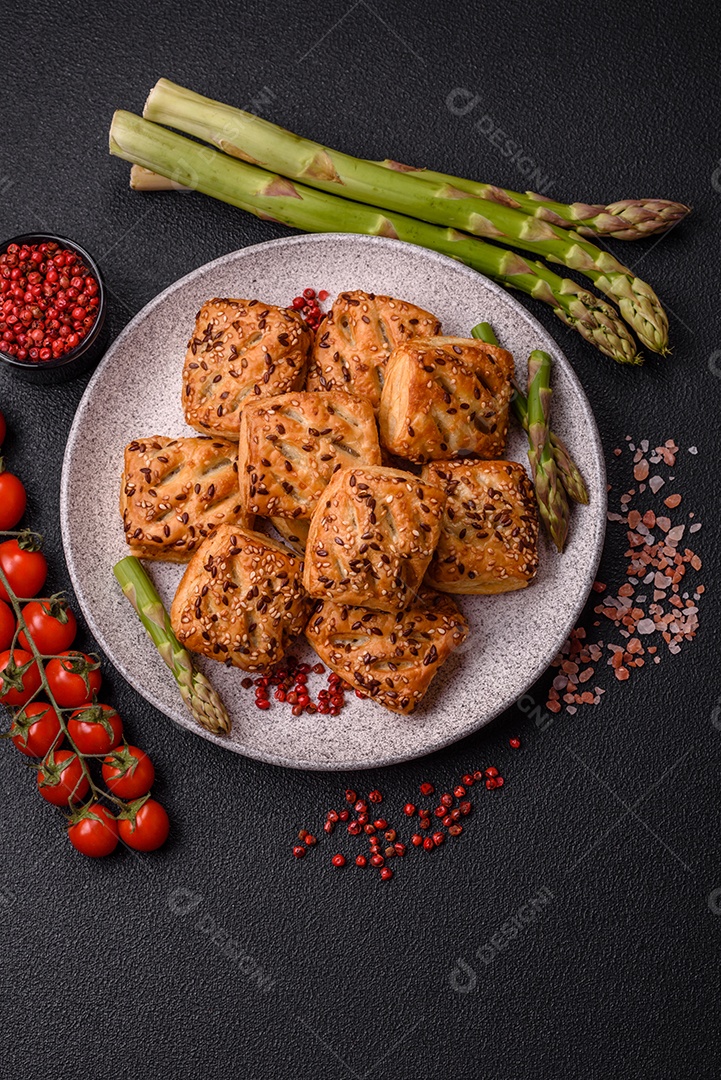Folhados triangulares com queijo feta, tomate com sal, especiarias e ervas sobre fundo escuro de concreto