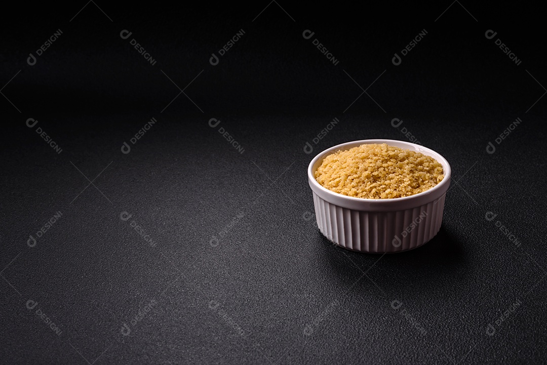 Massa anellini crua de trigo duro com sal e especiarias sobre um fundo escuro de concreto