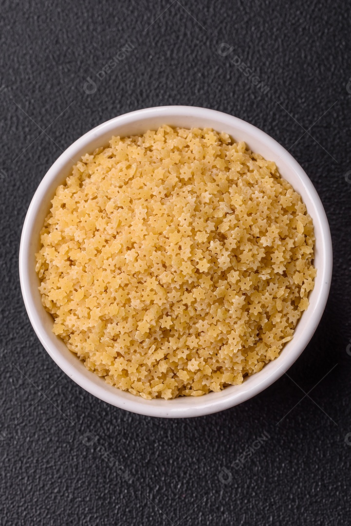 Massa anellini crua de trigo duro com sal e especiarias sobre um fundo escuro de concreto