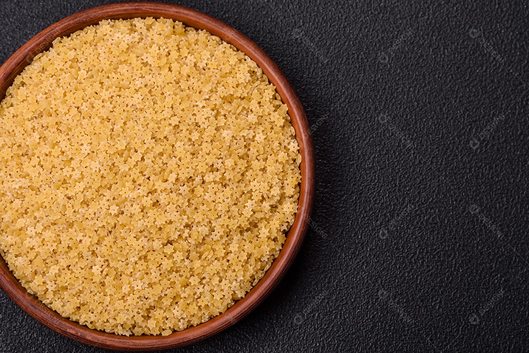 Massa anellini crua de trigo duro com sal e especiarias sobre um fundo escuro de concreto