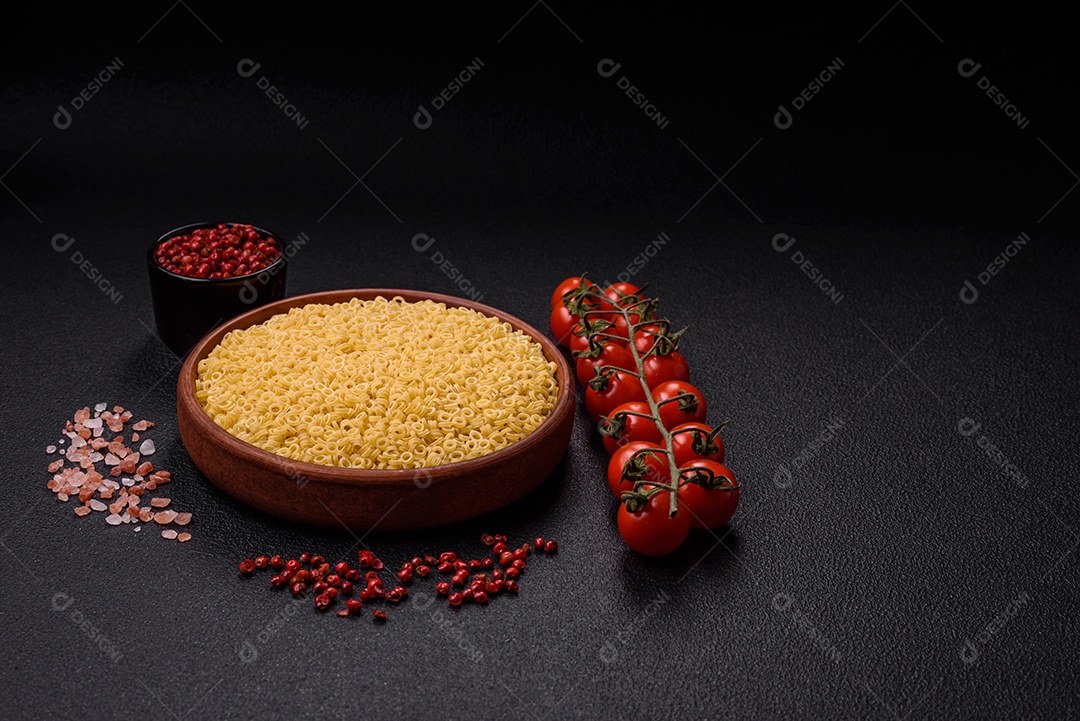 Massa anellini crua de trigo duro com sal e especiarias sobre um fundo escuro de concreto