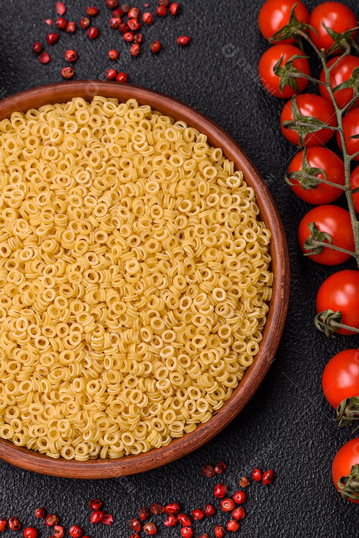 Massa anellini crua de trigo duro com sal e especiarias sobre um fundo escuro de concreto