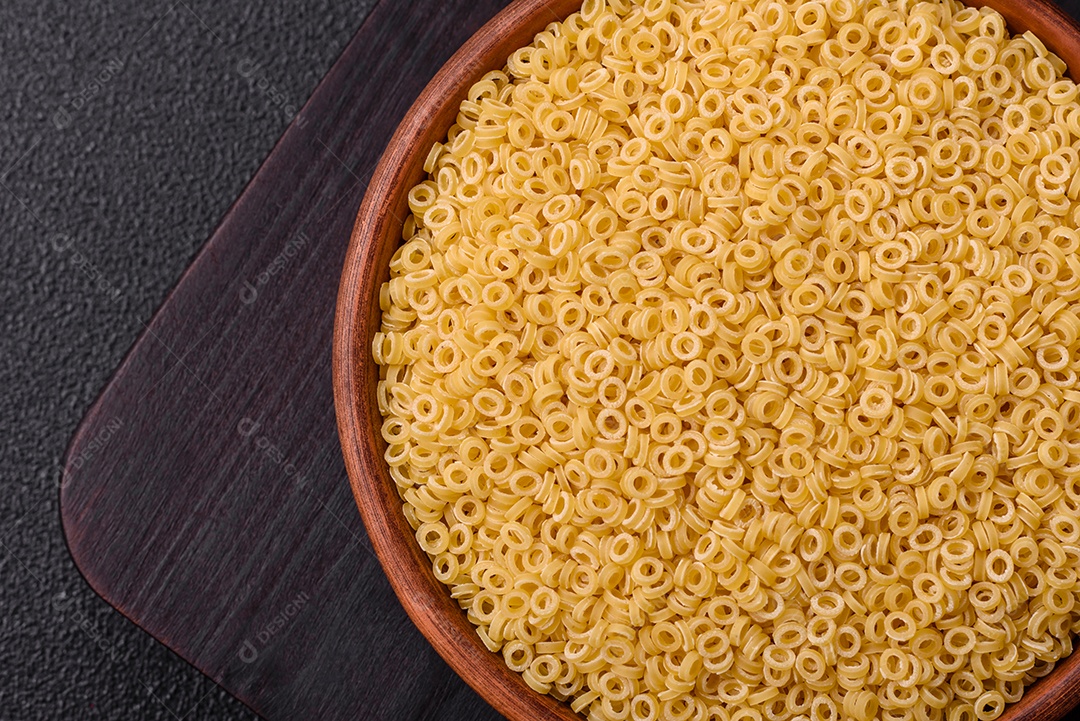 Massa anellini crua de trigo duro com sal e especiarias sobre um fundo escuro de concreto