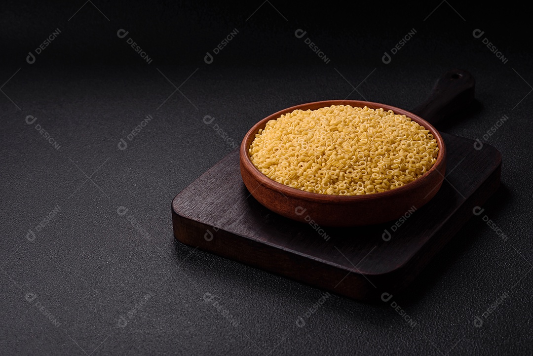 Massa anellini crua de trigo duro com sal e especiarias sobre um fundo escuro de concreto