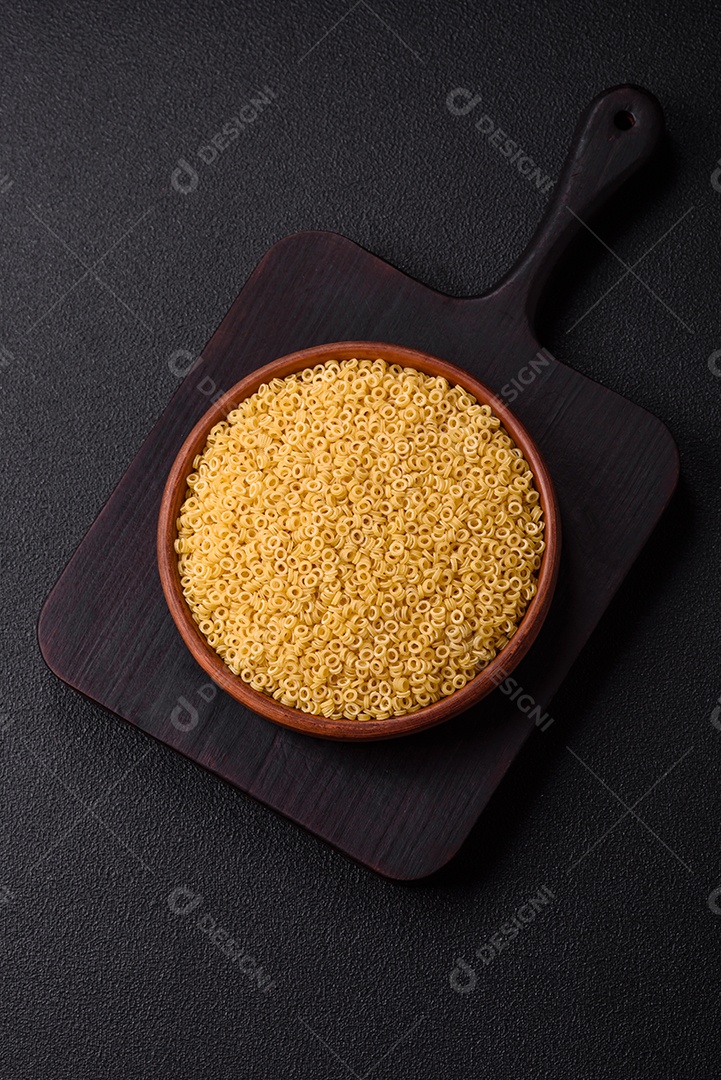 Massa anellini crua de trigo duro com sal e especiarias sobre um fundo escuro de concreto