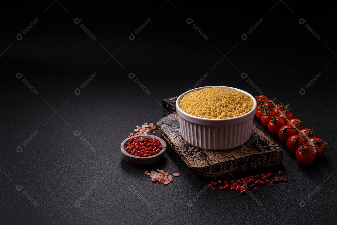 Massa anellini crua de trigo duro com sal e especiarias sobre um fundo escuro de concreto