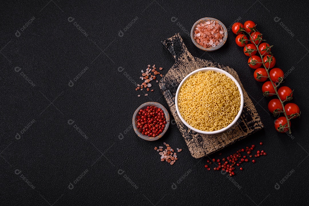 Massa anellini crua de trigo duro com sal e especiarias sobre um fundo escuro de concreto