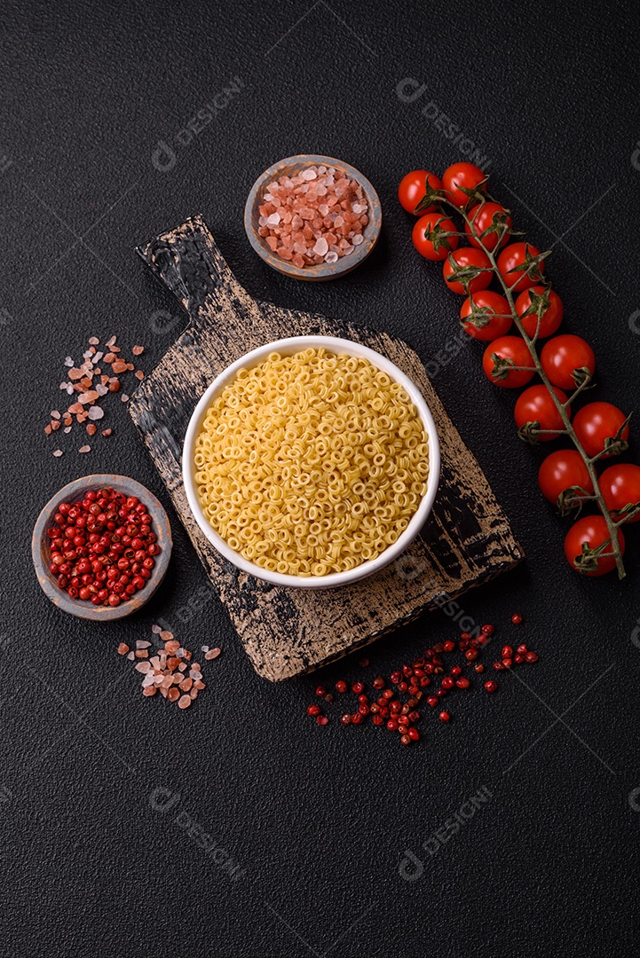 Massa anellini crua de trigo duro com sal e especiarias sobre um fundo escuro de concreto