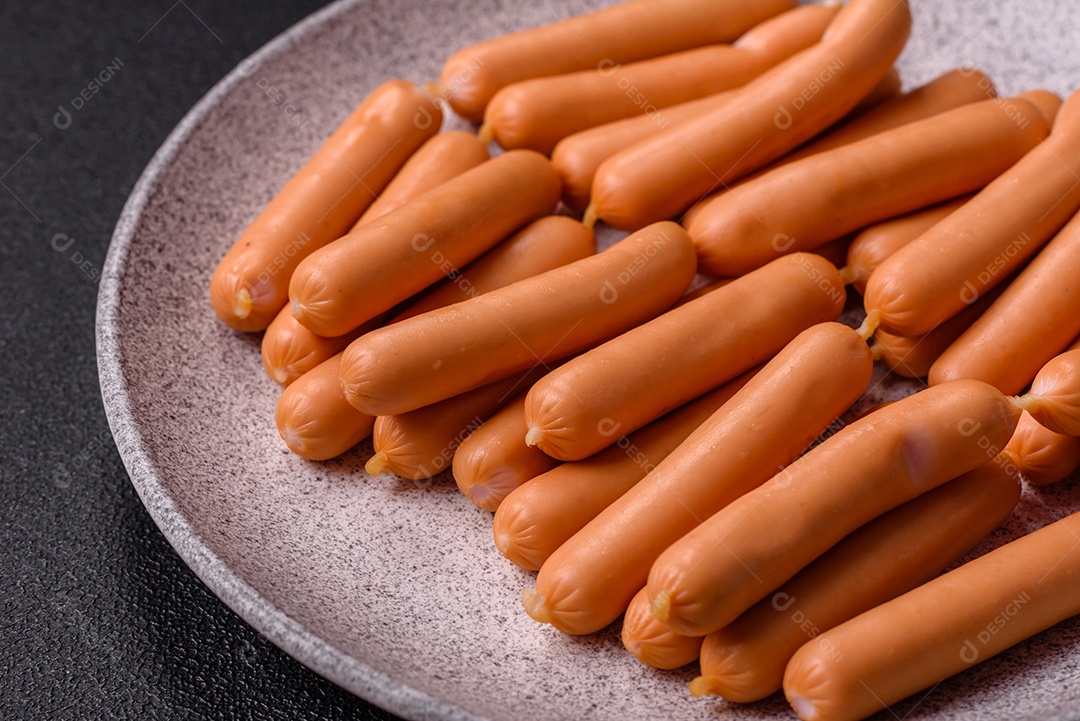 Deliciosas salsichas vegetarianas ou veganas com sal, especiarias e ervas sobre um fundo escuro de concreto