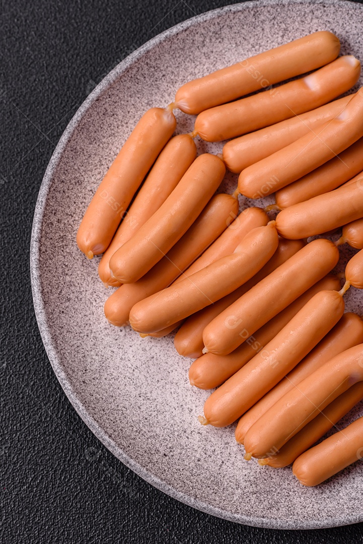 Deliciosas salsichas vegetarianas ou veganas com sal, especiarias e ervas sobre um fundo escuro de concreto