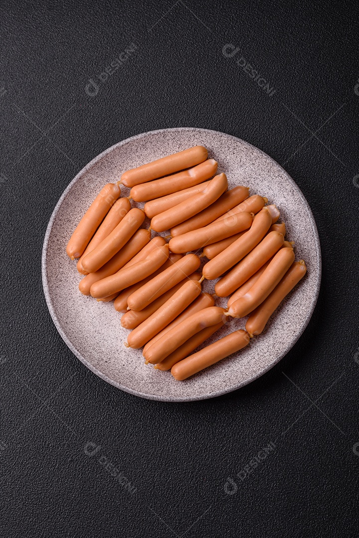 Deliciosas salsichas vegetarianas ou veganas com sal, especiarias e ervas sobre um fundo escuro de concreto