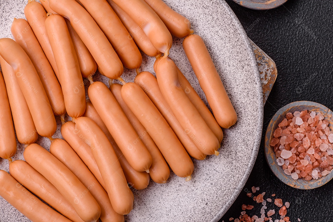 Deliciosas salsichas vegetarianas ou veganas com sal, especiarias e ervas sobre um fundo escuro de concreto
