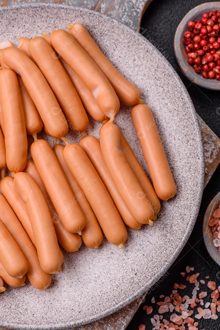 Deliciosas salsichas vegetarianas ou veganas com sal, especiarias e ervas sobre um fundo escuro de concreto