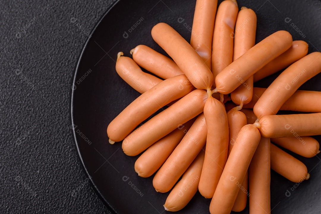 Deliciosas salsichas vegetarianas ou veganas com sal, especiarias e ervas sobre um fundo escuro de concreto