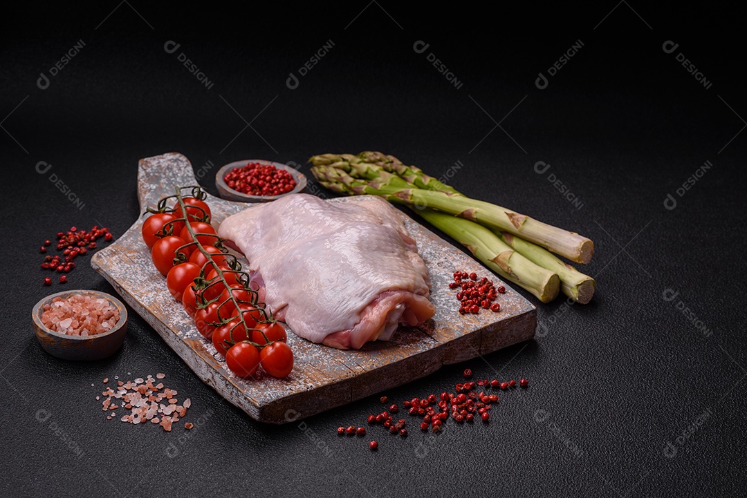 Pernas de frango cru com sal, especiarias e ervas sobre um fundo escuro de concreto