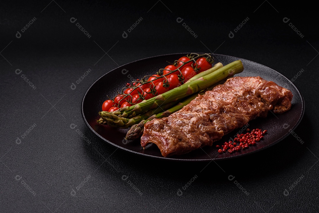 Costelas de porco cruas marinadas com sal, especiarias e ervas sobre um fundo escuro de concreto