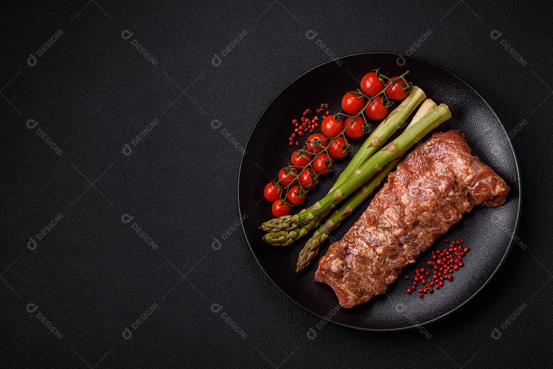 Costelas de porco cruas marinadas com sal, especiarias e ervas sobre um fundo escuro de concreto
