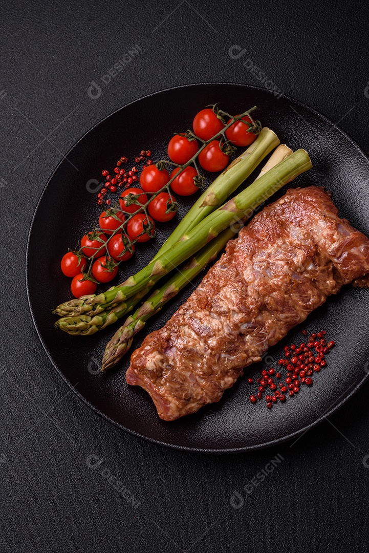 Costelas de porco cruas marinadas com sal, especiarias e ervas sobre um fundo escuro de concreto