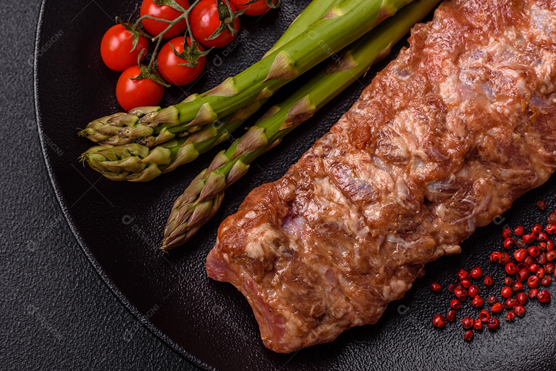 Costelas de porco cruas marinadas com sal, especiarias e ervas sobre um fundo escuro de concreto