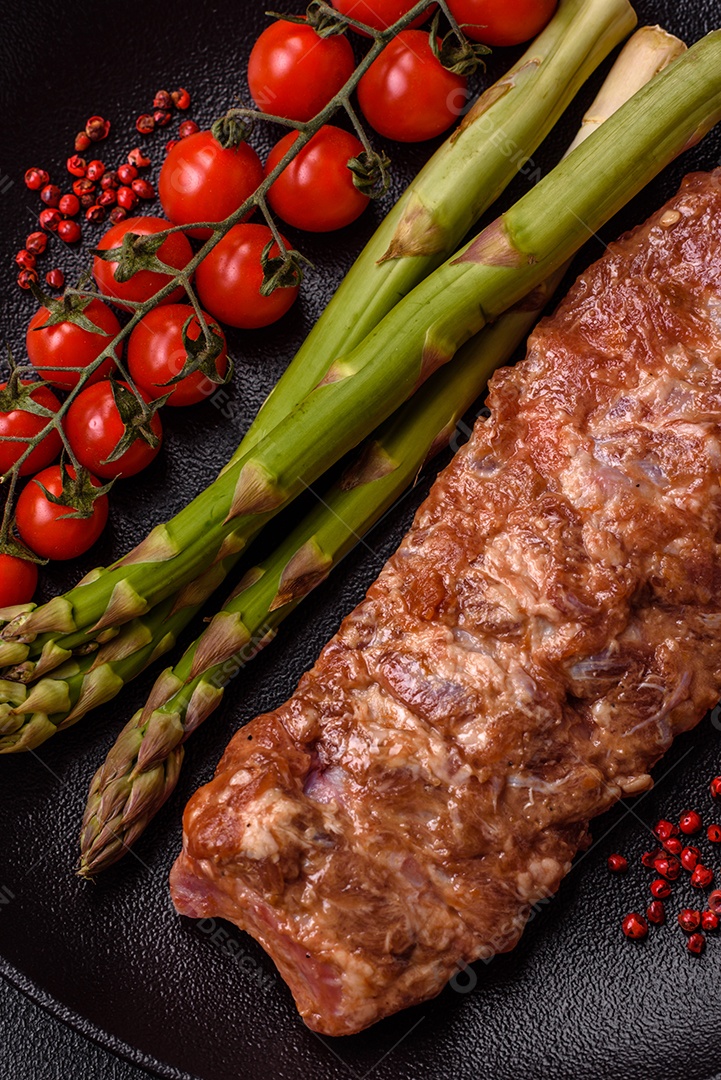 Costelas de porco cruas marinadas com sal, especiarias e ervas sobre um fundo escuro de concreto
