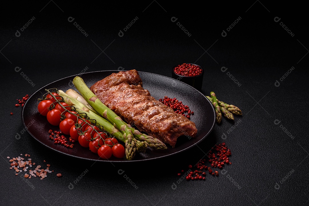 Costelas de porco cruas marinadas com sal, especiarias e ervas sobre um fundo escuro de concreto