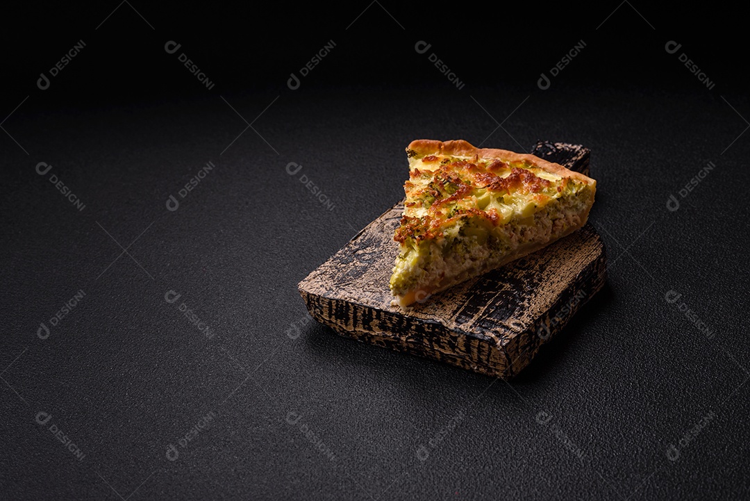 Deliciosa quiche com brócolis, queijo, frango, especiarias e ervas sobre um fundo escuro de concreto
